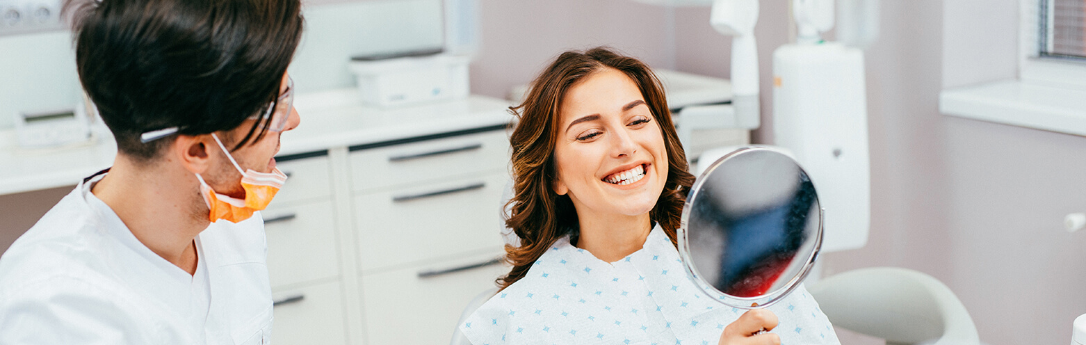 woman examining her smile in a mirror