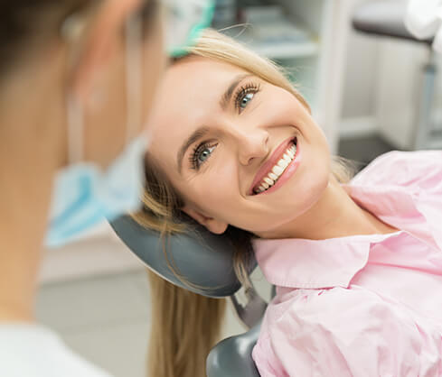 woman smiling as she talks with her dentist