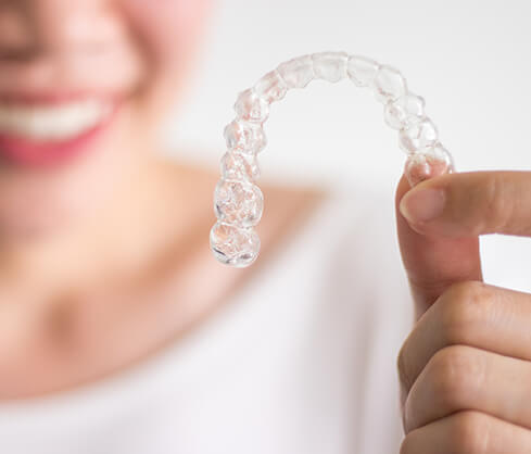 woman holding up a clear aligner