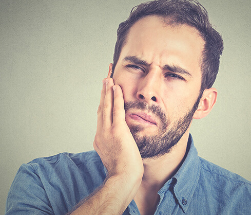 man holding his jaw in pain